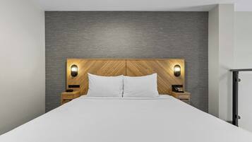 Una cama con cabecera de madera, dos lámparas de noche, una mesita de noche y un armario.