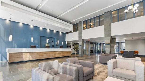 A spacious lobby with a reception desk, seating area, and a high ceiling with natural light. - Sandman Hotels & Suites Calgary West (Calgary)