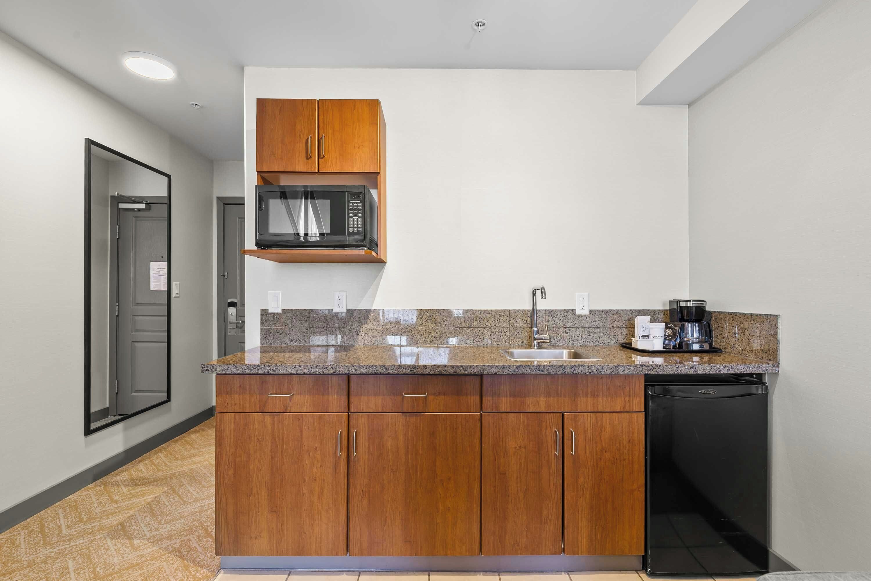 Una cocina con gabinetes de madera, microondas, cafetera y lavavajillas.