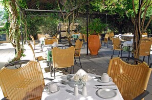 Guests can dine al fresco under a pergola surrounded by lush greenery.