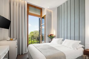 Relax in comfort with a large bed against a stylish wall panel, featuring a TV and sliding glass door to a balcony with a view.