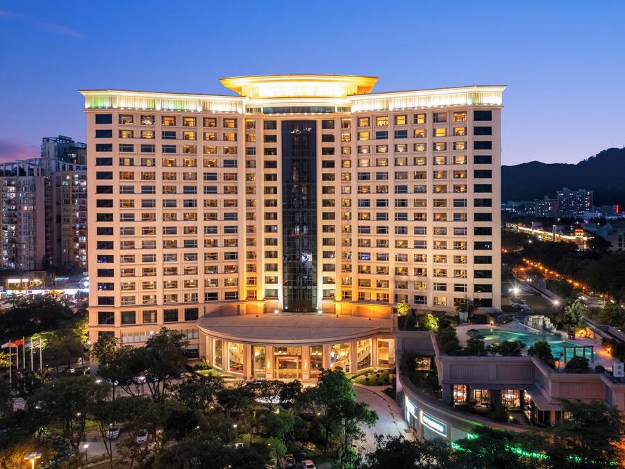 A high-rise hotel with a central atrium, multiple floors, and a well-lit facade.