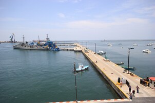 Un puerto con barcos amarrados, un muelle y un barco grande al fondo.