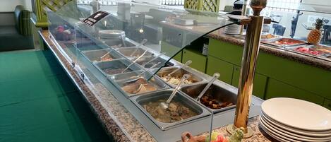 A buffet area with various food options and a fruit bowl.