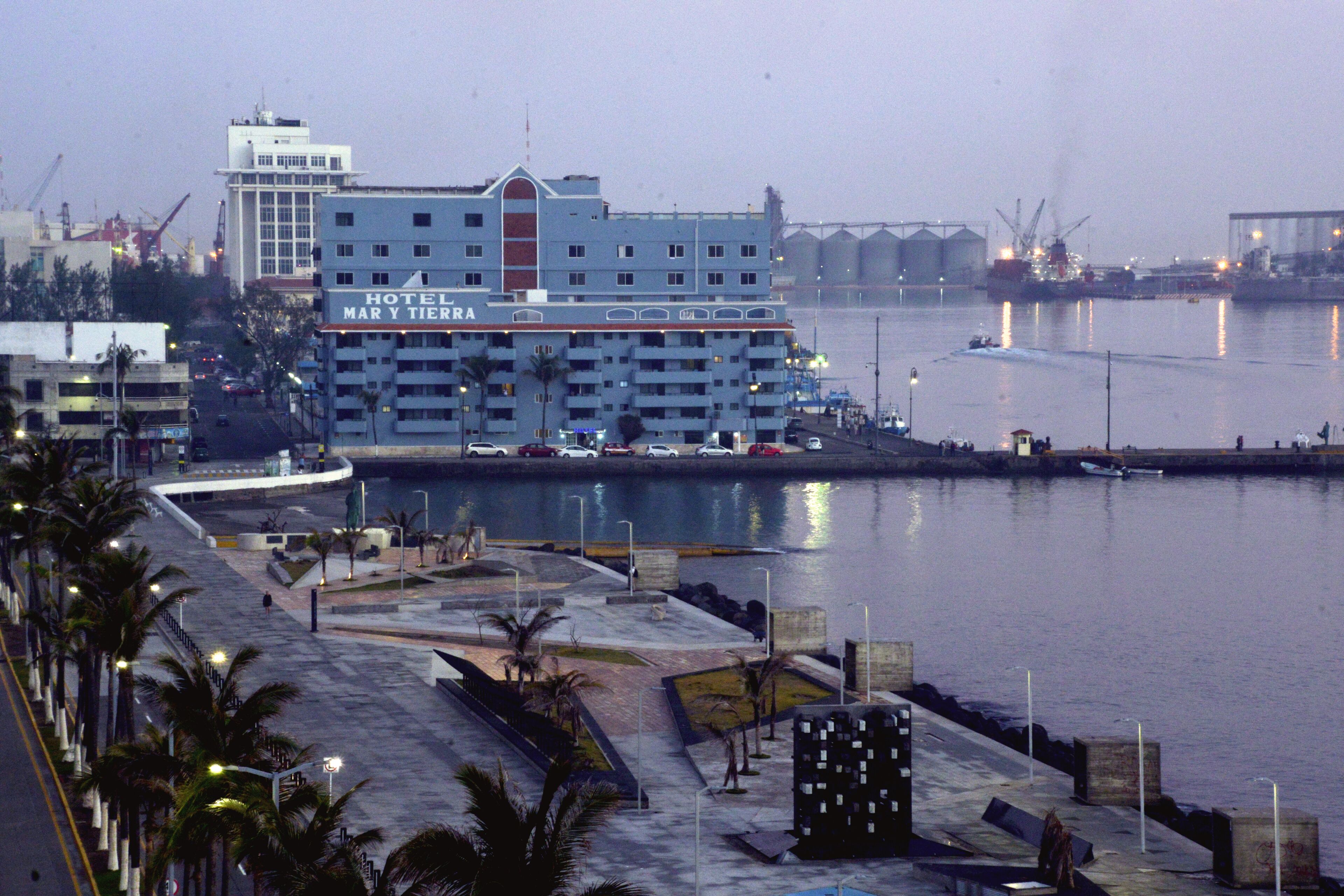 A hotel with a large building by the waterfront, featuring a prominent sign.