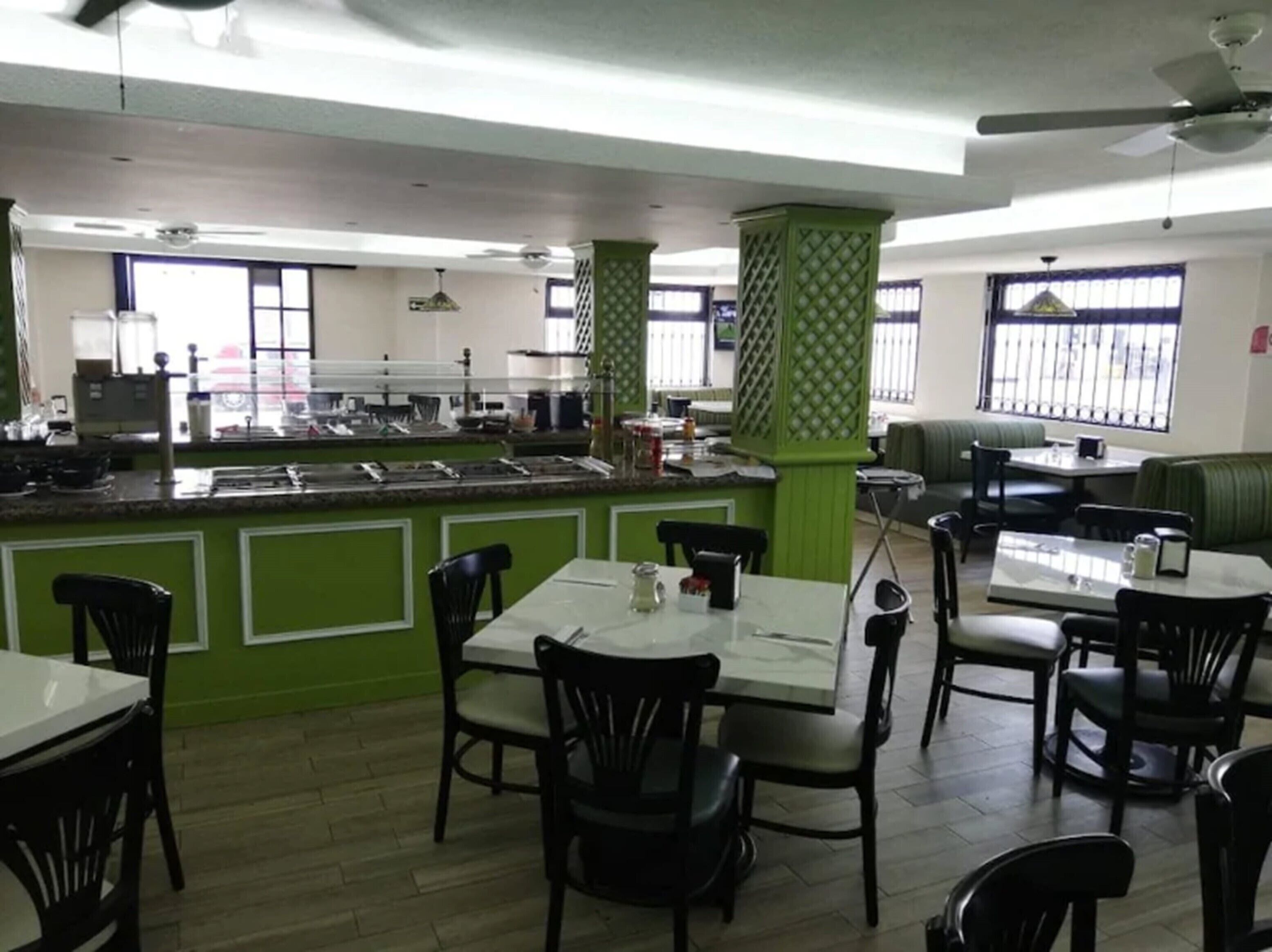 A restaurant with a counter, tables, and chairs.