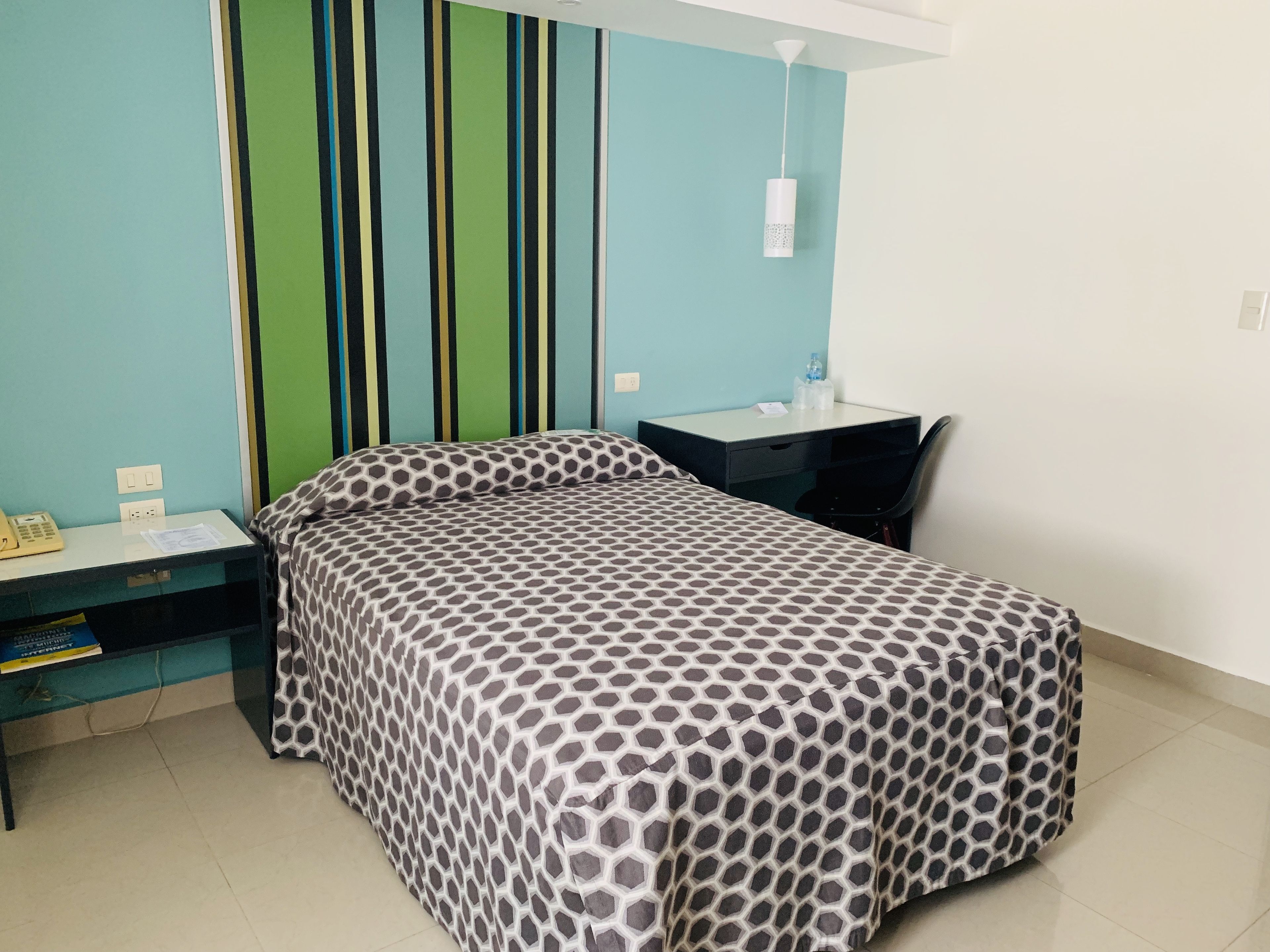 A bedroom with a bed, a desk, and a chair.