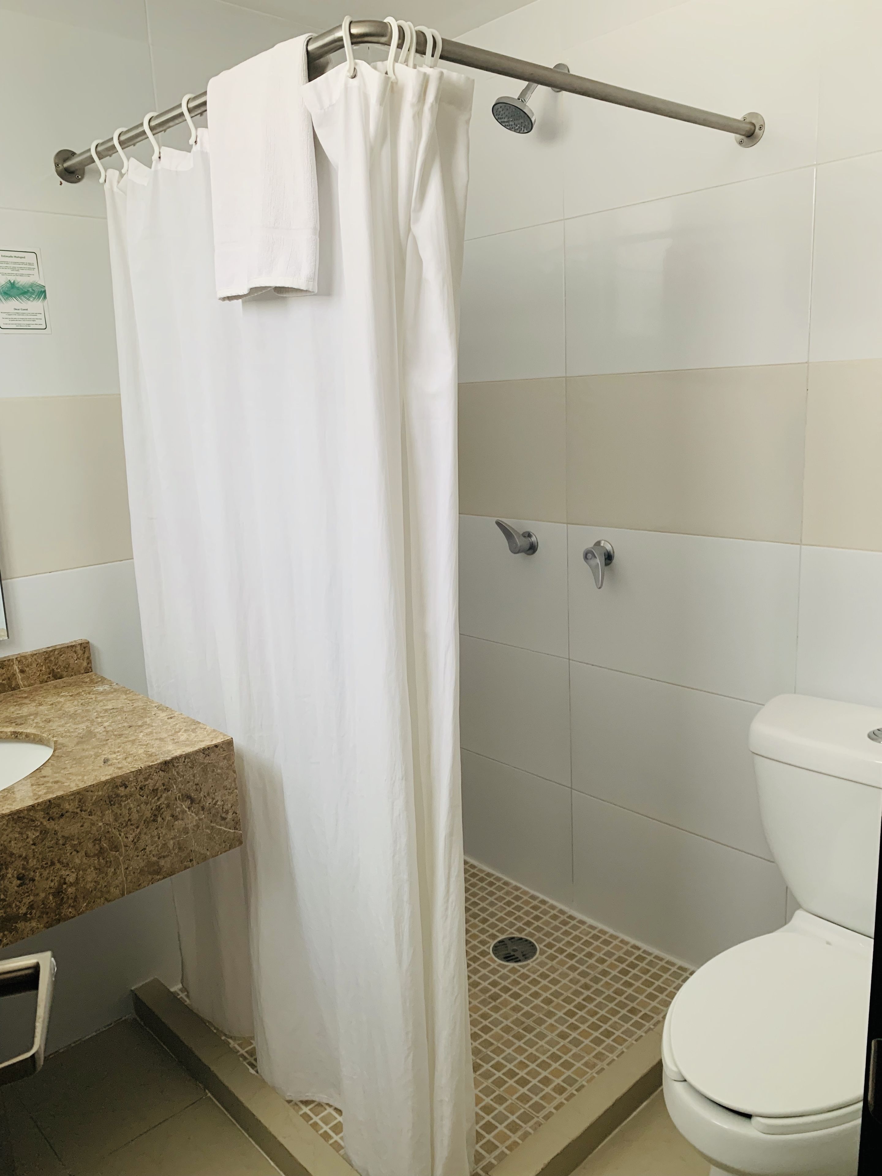 A bathroom with a shower curtain, a toilet, and a sink.