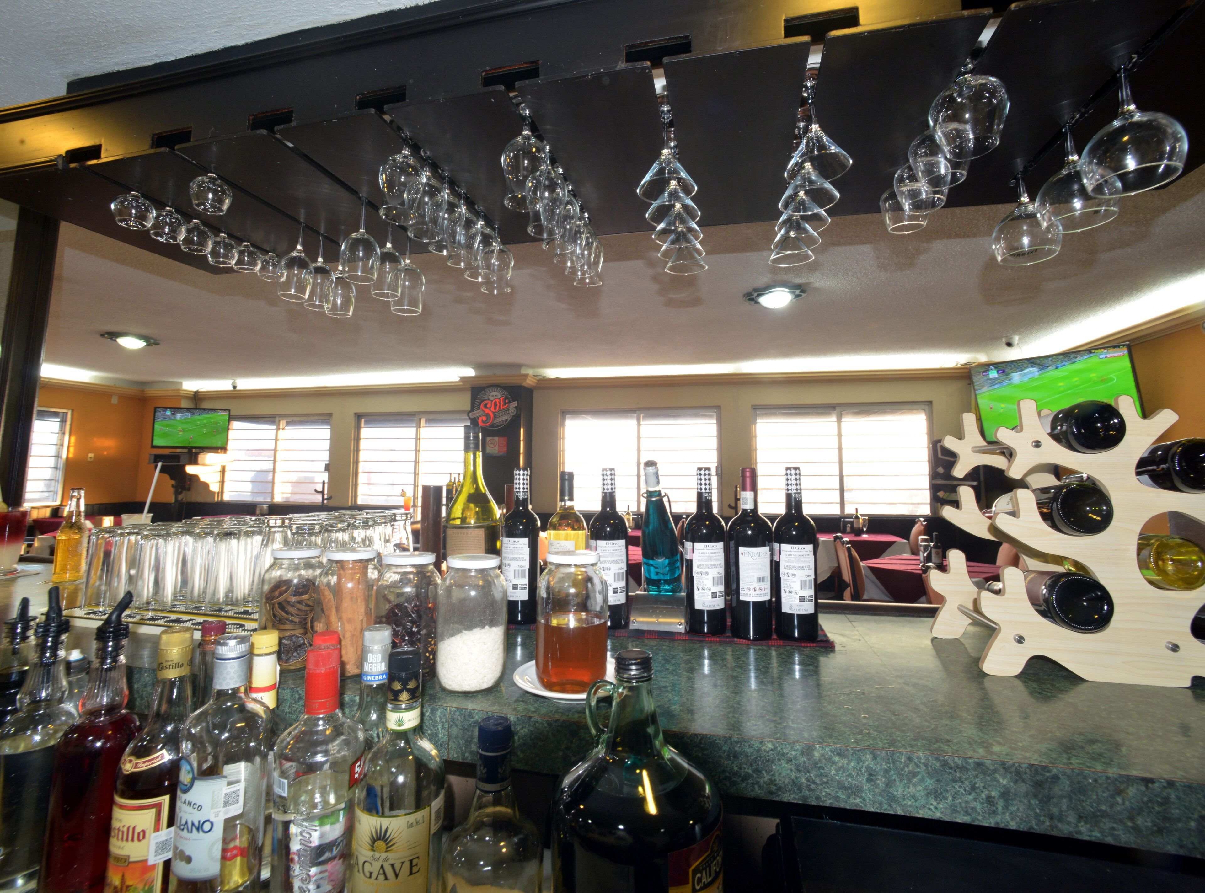 Zona de bar con varias botellas y vasos.