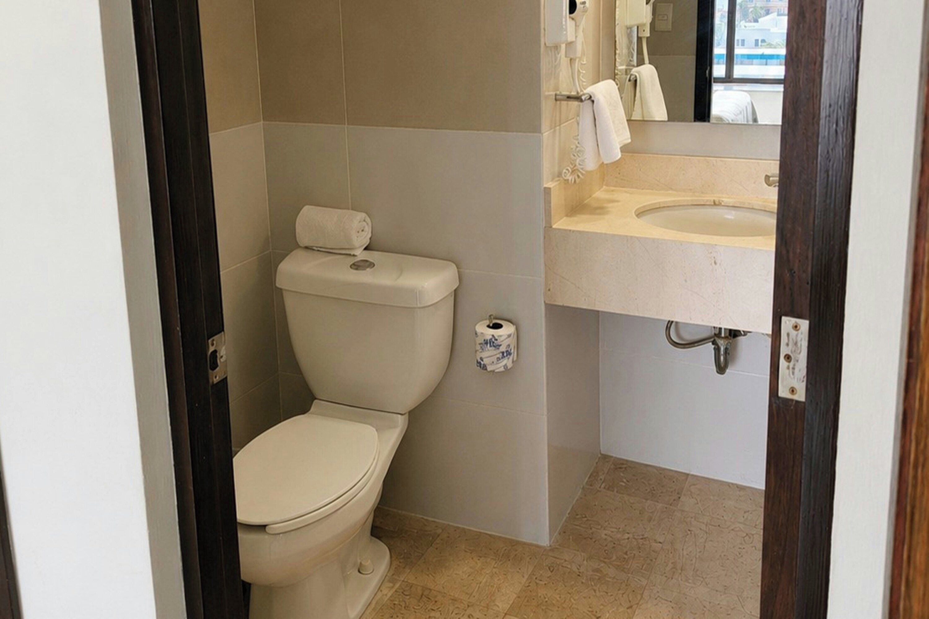 Un bagno piccolo con il water, un lavandino e uno specchio.