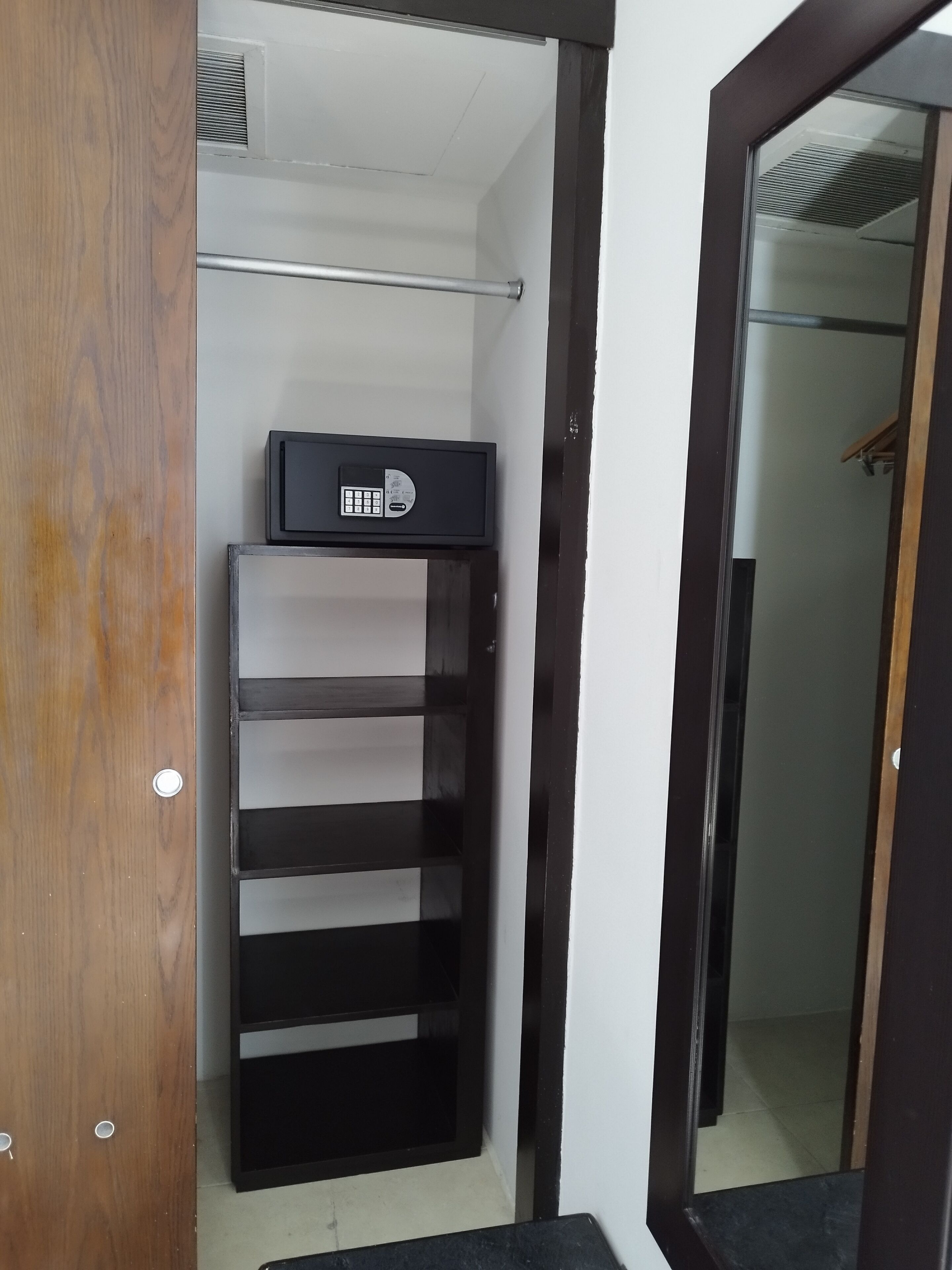 A closet with a black storage unit, shelves, and a hanging rod.