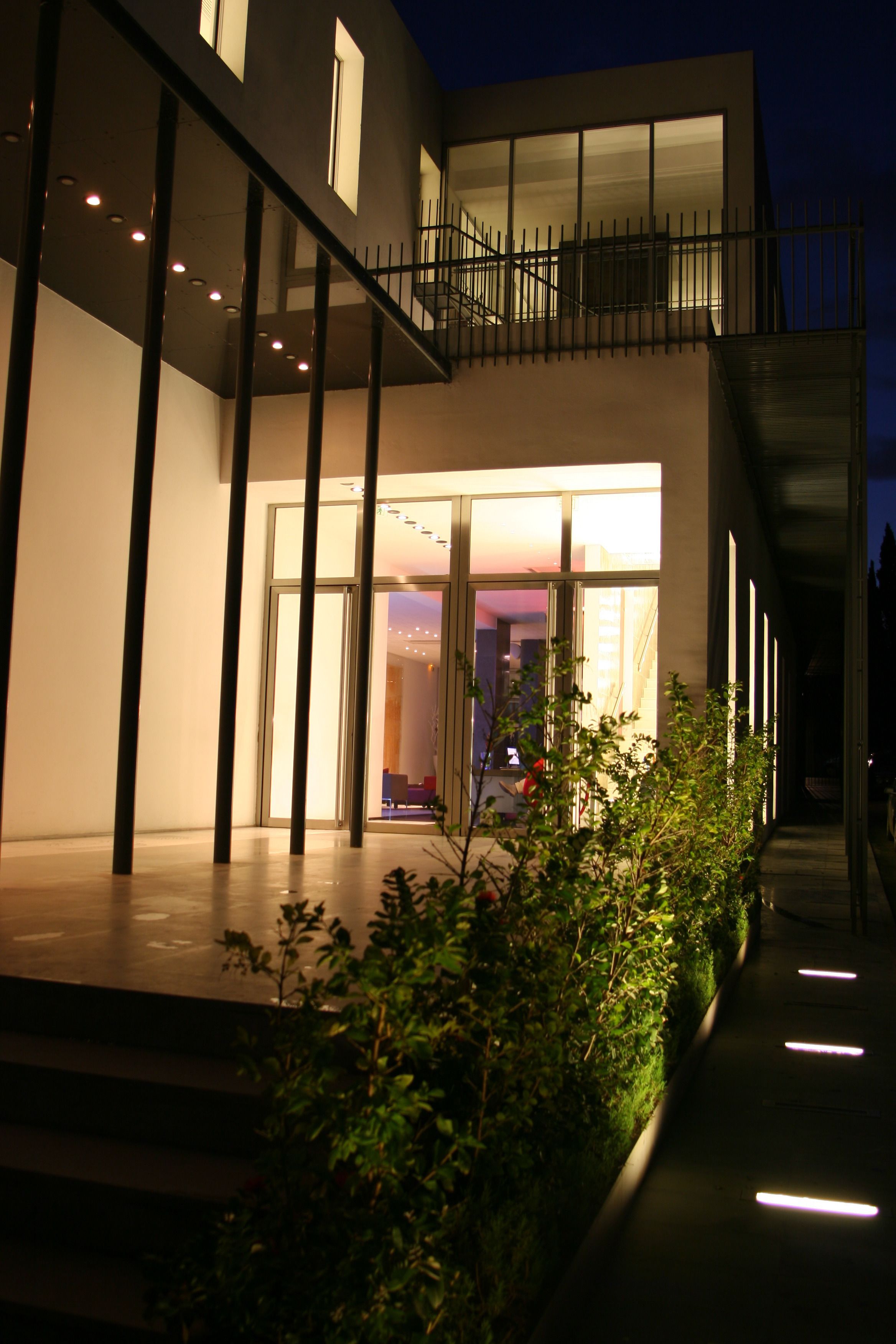 A modern building with a glass entrance, a staircase, and a balcony.