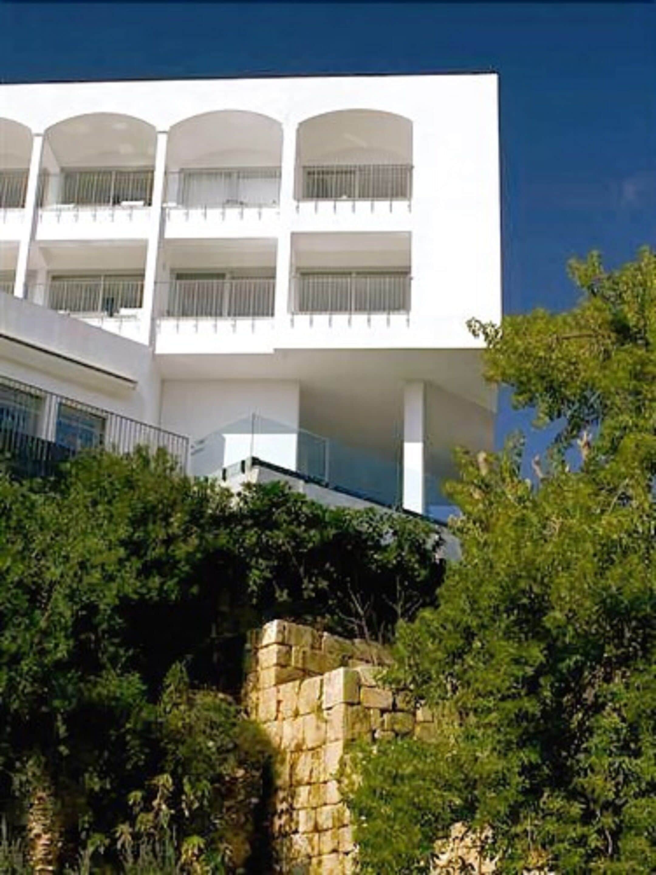 Un bâtiment moderne doté de nombreux balcons et d’un mur de soutènement en pierre.
