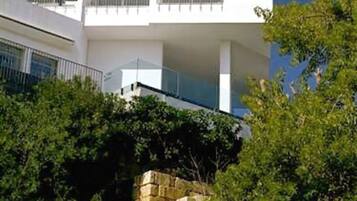 Un bâtiment moderne doté de nombreux balcons et d’un mur de soutènement en pierre.