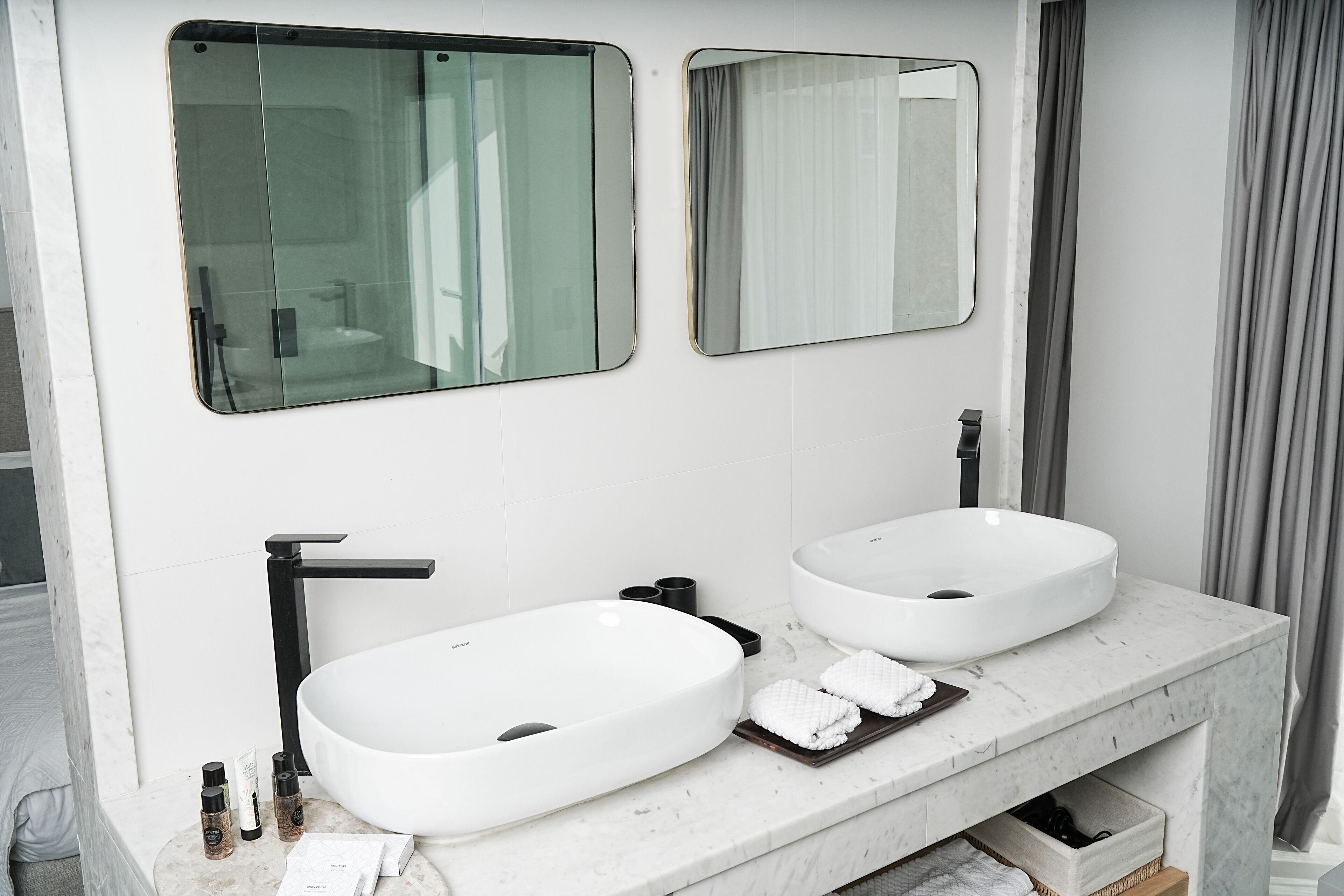 Une salle de bain moderne avec deux lavabos blancs, un robinet noir et un miroir.