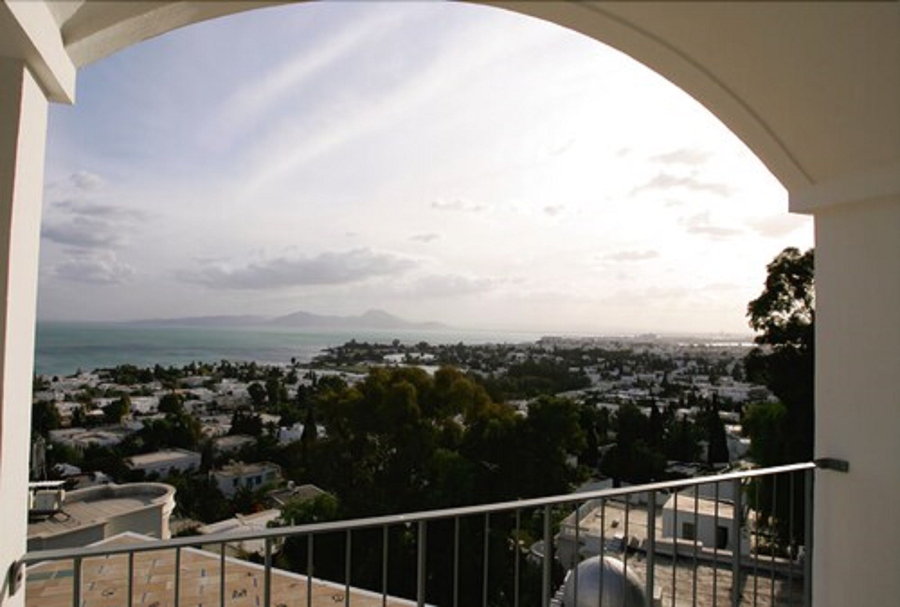 A balcony with a view of a coastal town and the sea.