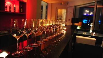 Una hilera de copas de vino vacías sobre una barra en un cuarto con poca luz y una iluminación ambiental roja.