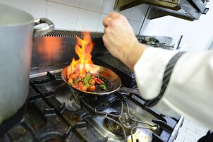 A chef cooking with a pan on a stove.