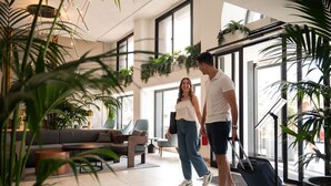 A modern hotel lobby with a sofa, a coffee table, and potted plants. - Luna Holiday Complex (Mellieha)