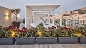 A rooftop terrace with a covered seating area, potted plants, and a view of the cityscape. - Luna Holiday Complex (Mellieha)