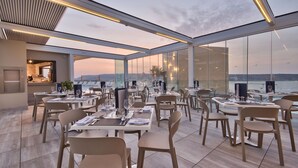 A modern restaurant with a terrace overlooking the sea, featuring contemporary furniture and a clear view of the horizon. - Luna Holiday Complex (Mellieha)