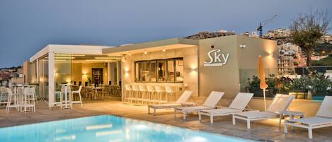 A poolside area with lounge chairs and a bar.