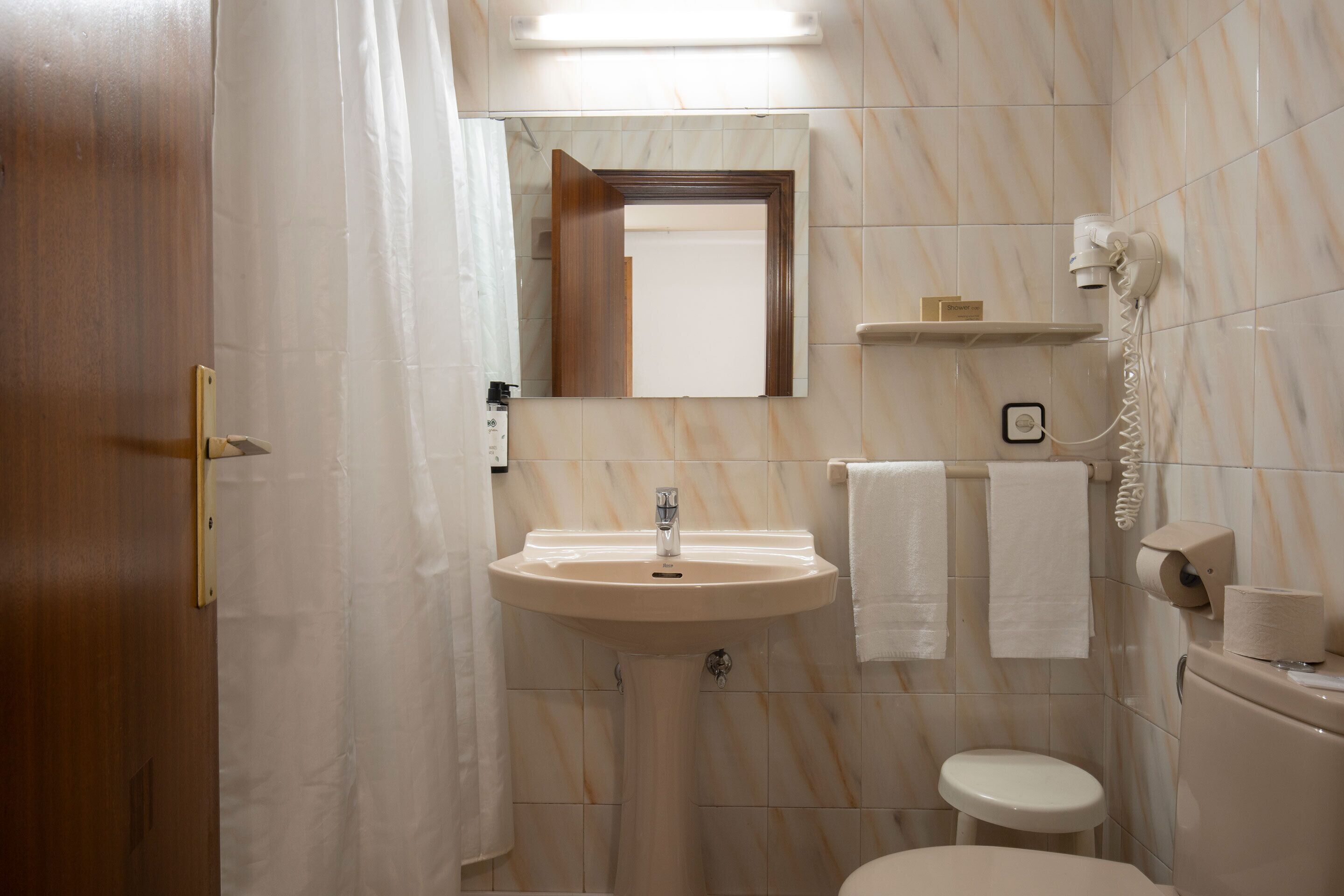 Une salle de bain équipée d’un lavabo, d’un miroir, de toilettes et d’un porte-serviettes.