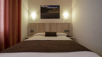 Una habitación de hotel con una cama, una mesita de noche, una lámpara y un cuadro colgado en la pared.