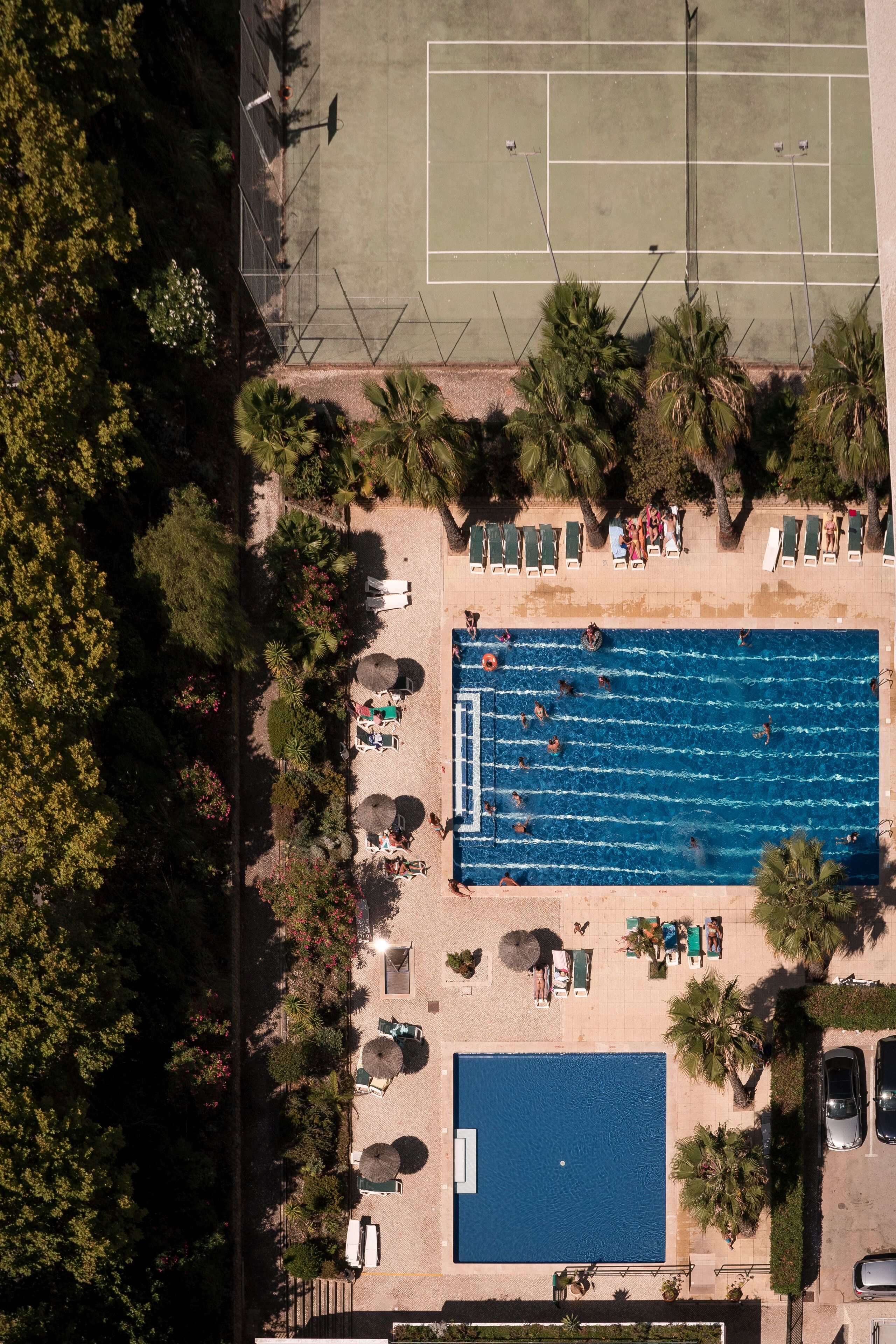 Vue aérienne d’un complexe hôtelier doté d’une piscine, de courts de tennis et d’espaces de détente.
