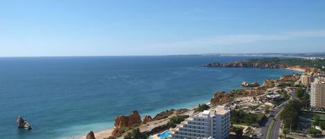 A coastal resort area with buildings, a beach, and a clear view of the sea.