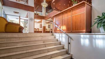 A grand staircase leading to a wooden reception desk with a potted plant.