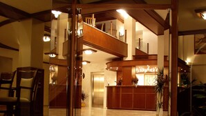 A spacious lobby with a marble staircase leading to a second floor, a reception desk, and a dining area with chairs. - Diana Hotel (Zakynthos)