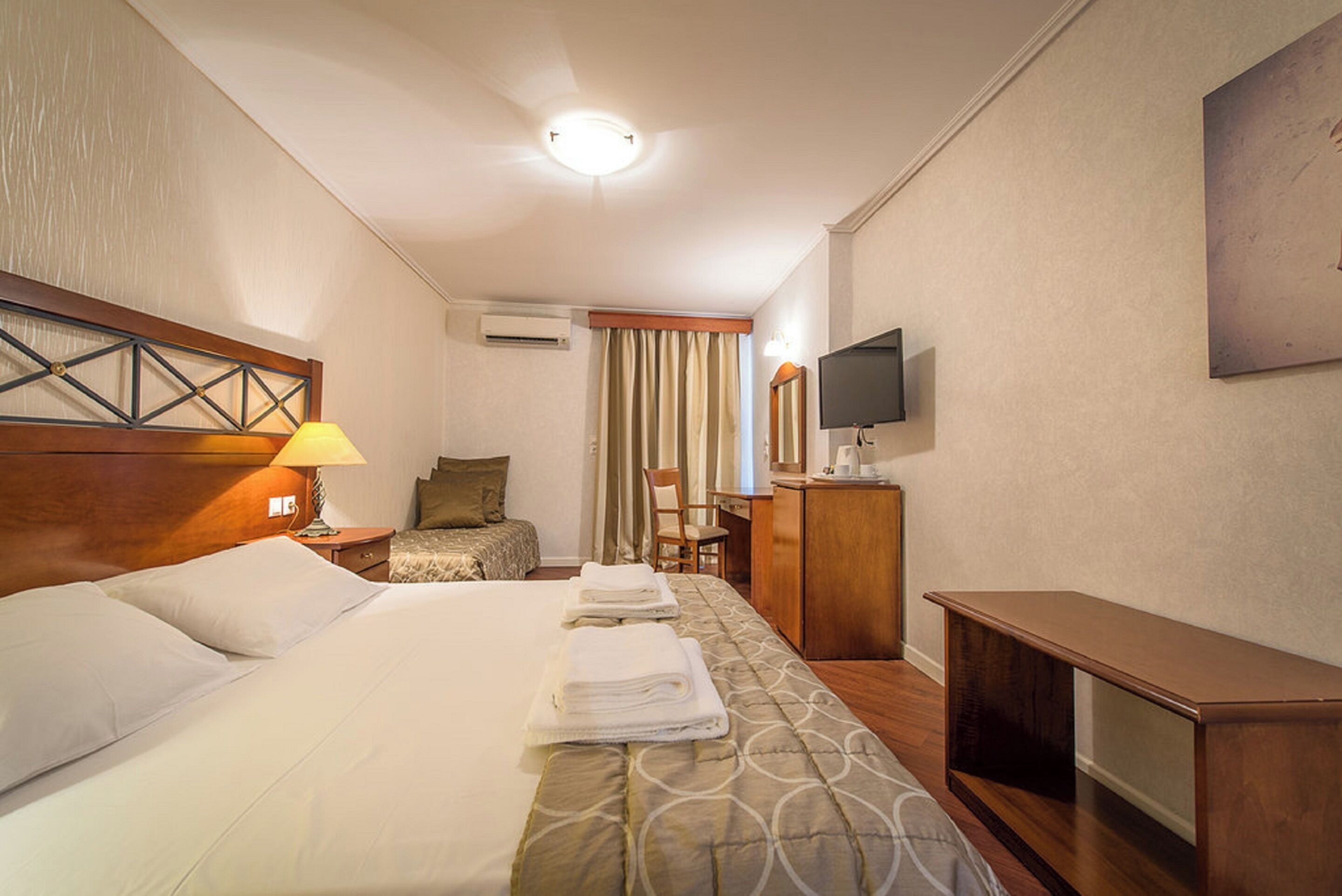 Una habitación de hotel con una cama grande, un escritorio, un televisor y una silla.