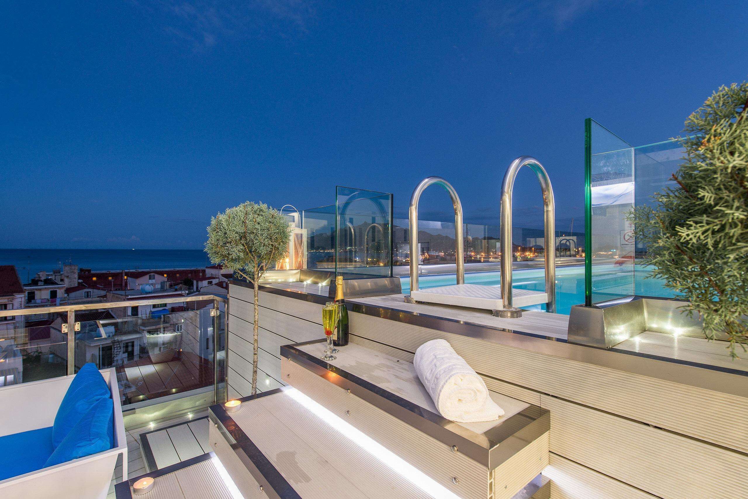 Una terraza en la azotea con piscina, zona de estar y vistas al mar.
