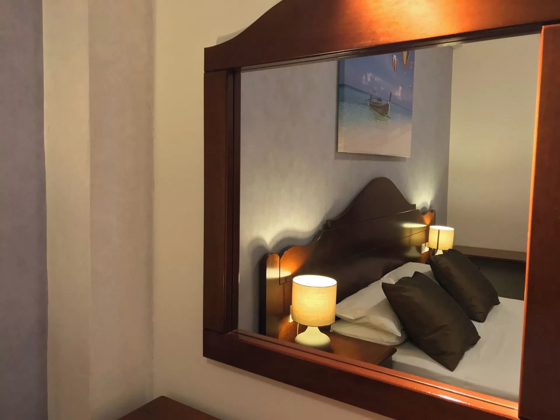Ein Hotelzimmer mit einem großen Spiegel, einem Bett mit Kissen und zwei Nachttischlampen.