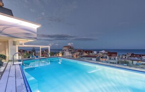 A rooftop pool with a clear view of the sea and surrounding buildings.