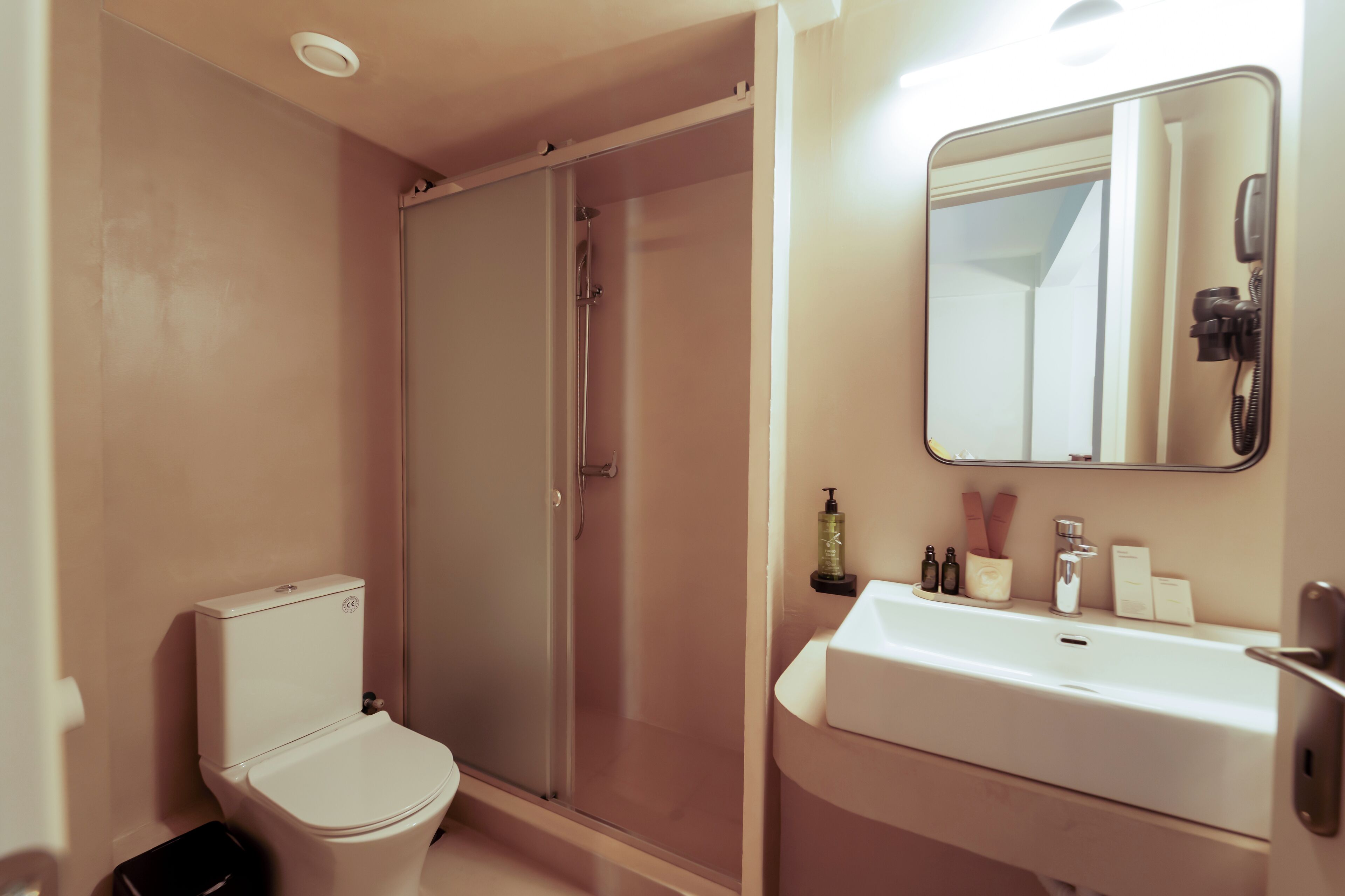 A bathroom with a toilet, a glass-enclosed shower, and a sink with a mirror above it.