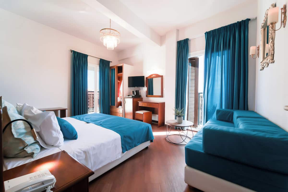Ein Hotelzimmer mit Bett, einer Couch, einem Schreibtisch, einem Fernseher und einem Spiegel.