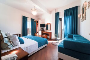 Una camera d'albergo con un letto, un divano, una scrivania, una televisione e uno specchio.
