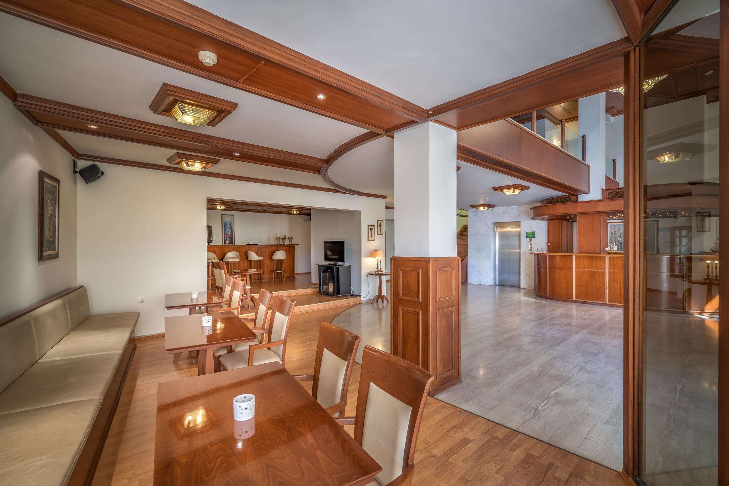 Un comedor amplio con mesas y sillas de madera, una cocina al fondo y una escalera que sube a un nivel superior.