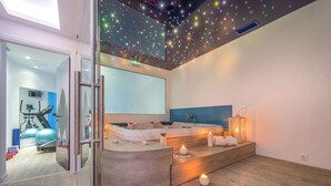 A modern spa room with a starry ceiling, a massage table, and a visible exercise area with equipment. - Diana Hotel (Zakynthos)