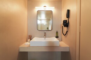 Un bagno con un lavandino bianco, uno specchio, un telefono cellulare e un porta asciugamani.