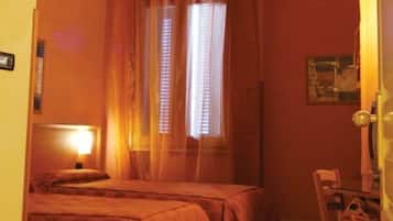 Una camera d'albergo con due letti, una scrivania e una sedia.