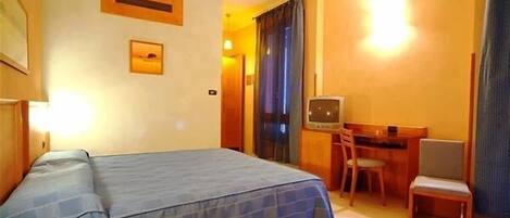 Ein Hotelzimmer mit einem Bett, einem Schreibtisch, einem Sessel und einem Fernseher.