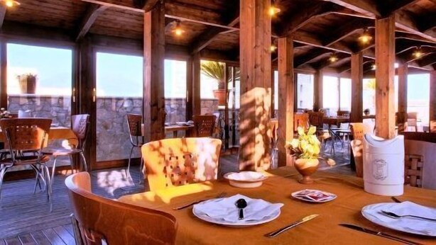 An outdoor dining area with wooden beams, tables set for two, and chairs. - Hotel Eden (Naples)