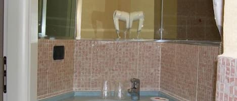 Un baño con lavamanos, espejo y perchero para toallas.