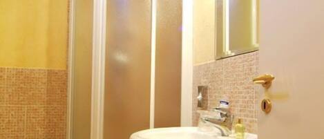Ein Badezimmer mit Dusche, Waschbecken und Spiegel.