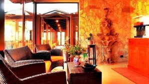 A room with wicker furniture, a stone wall, and a view of the outside. - Hotel Eden (Naples)
