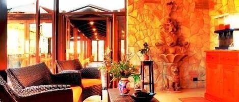 A room with wicker furniture, a stone wall, and a view of the outside.