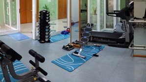 Un gimnasio con equipo de ejercicio, que incluye una cinta de correr, pesas y un espejo.